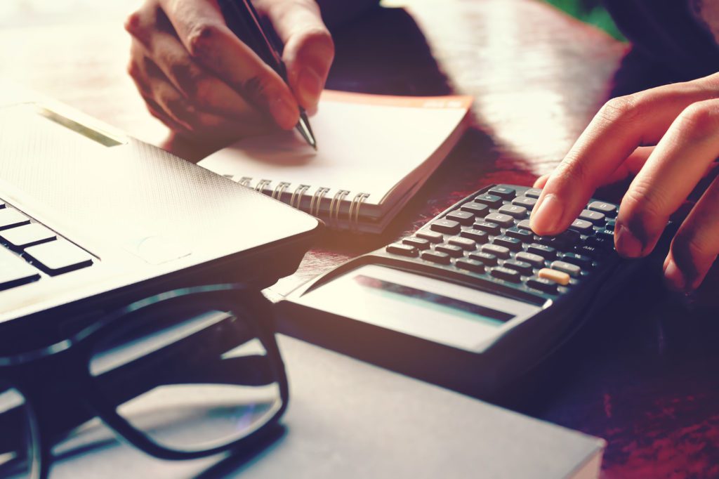 Person making an extraction equipment budget using a calculator and notepad